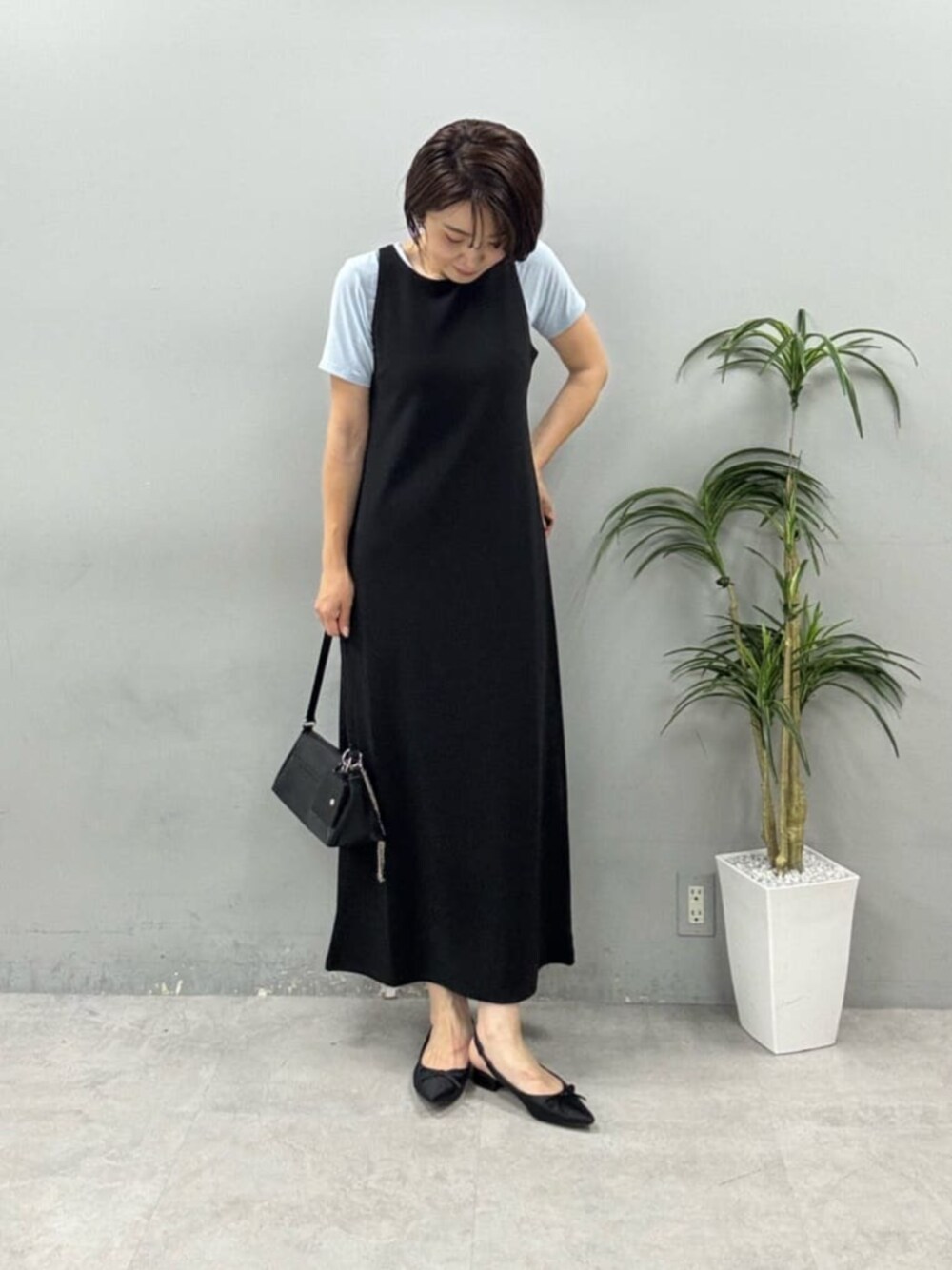 ブラック系のショルダーバッグ、ブラック系のワンピース、ブルー系のTシャツ/カットソーを着用したレディースの春コーディネートの1枚目の写真
