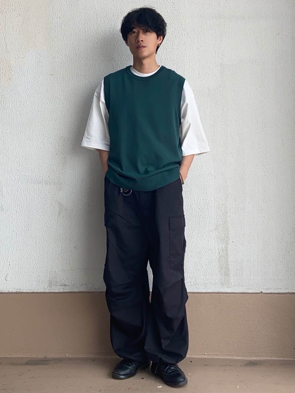 グリーン系のベスト、ホワイト系のTシャツ/カットソー、ブラック系のカーゴパンツを着用したメンズの春コーディネートの1枚目の写真