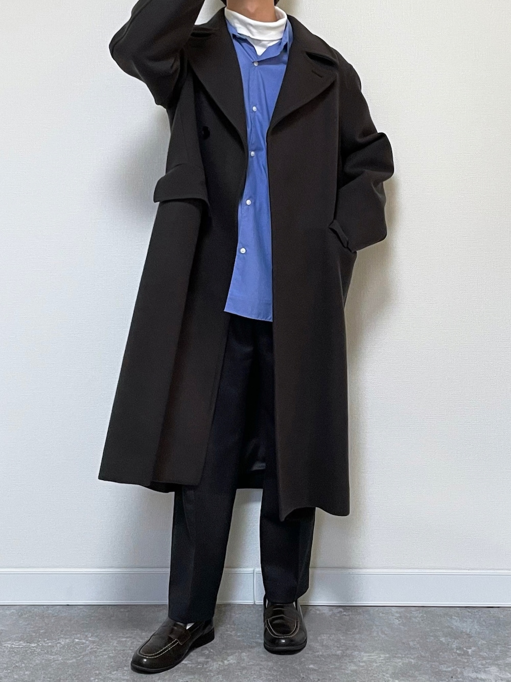 グレー系のチェスターコート、ブルー系のシャツ/ブラウス、ブラック系のスラックスを着用したメンズの冬コーディネートの1枚目の写真