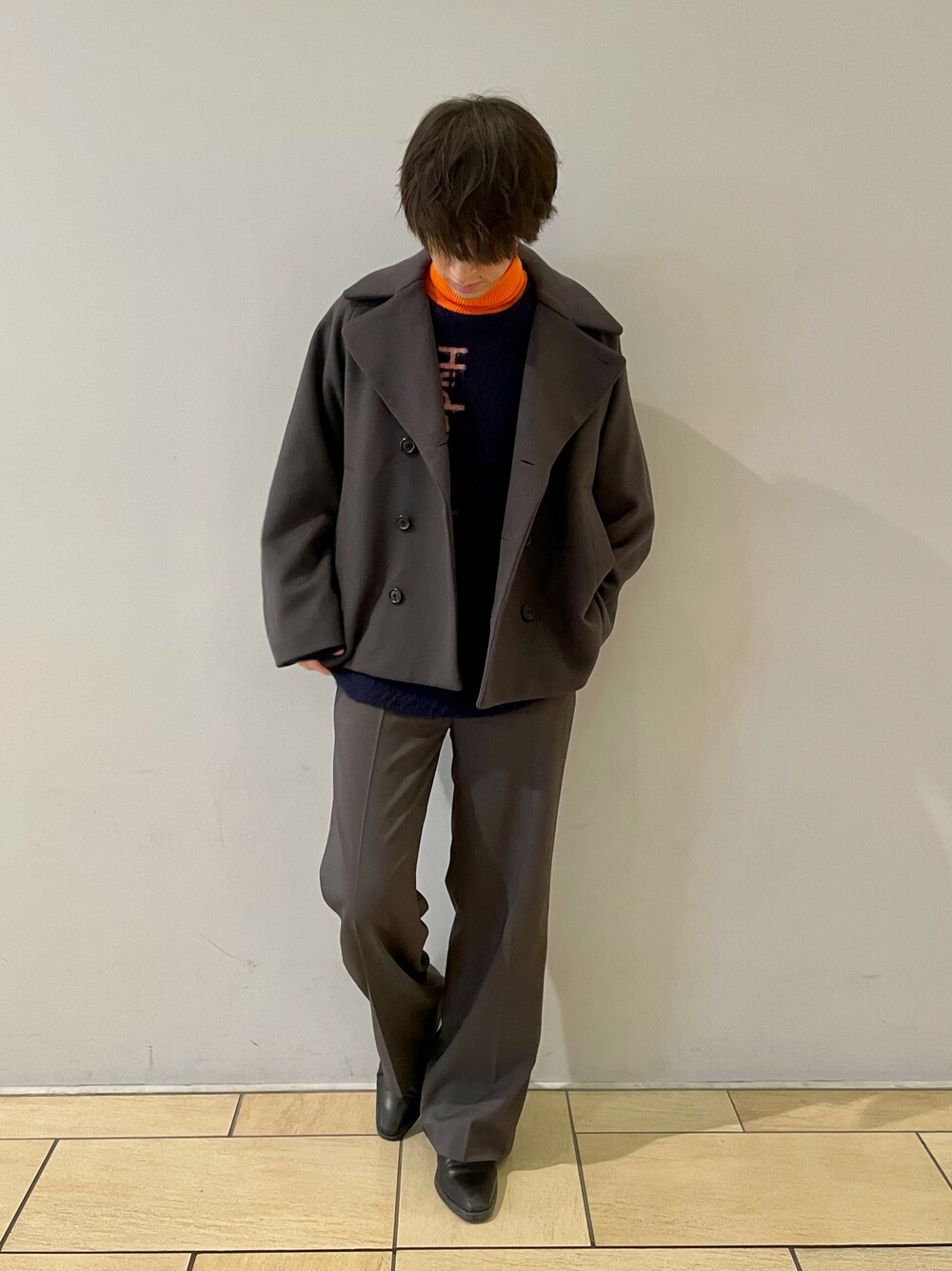 グレー系のピーコート、パープル系のニット/セーター、グレー系のスラックスを着用したメンズの冬コーディネートの1枚目の写真