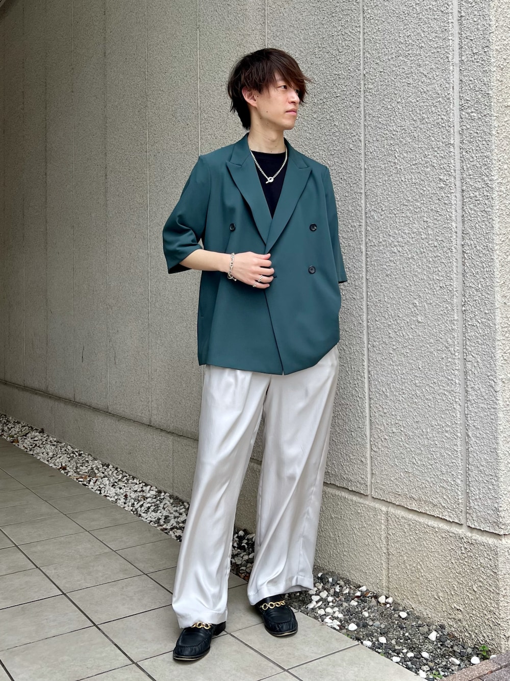 グリーン系のテーラードジャケット、グレー系のスラックス、シルバー系のネックレスを着用したメンズの春コーディネートの1枚目の写真