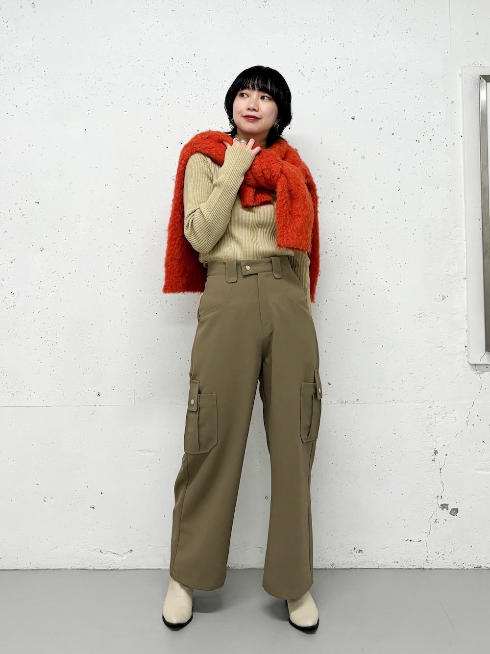 ベージュ系のニット/セーター、グリーン系のその他パンツ、オレンジ系のカーディガン/ボレロを着用したレディースの冬コーディネートの1枚目の写真