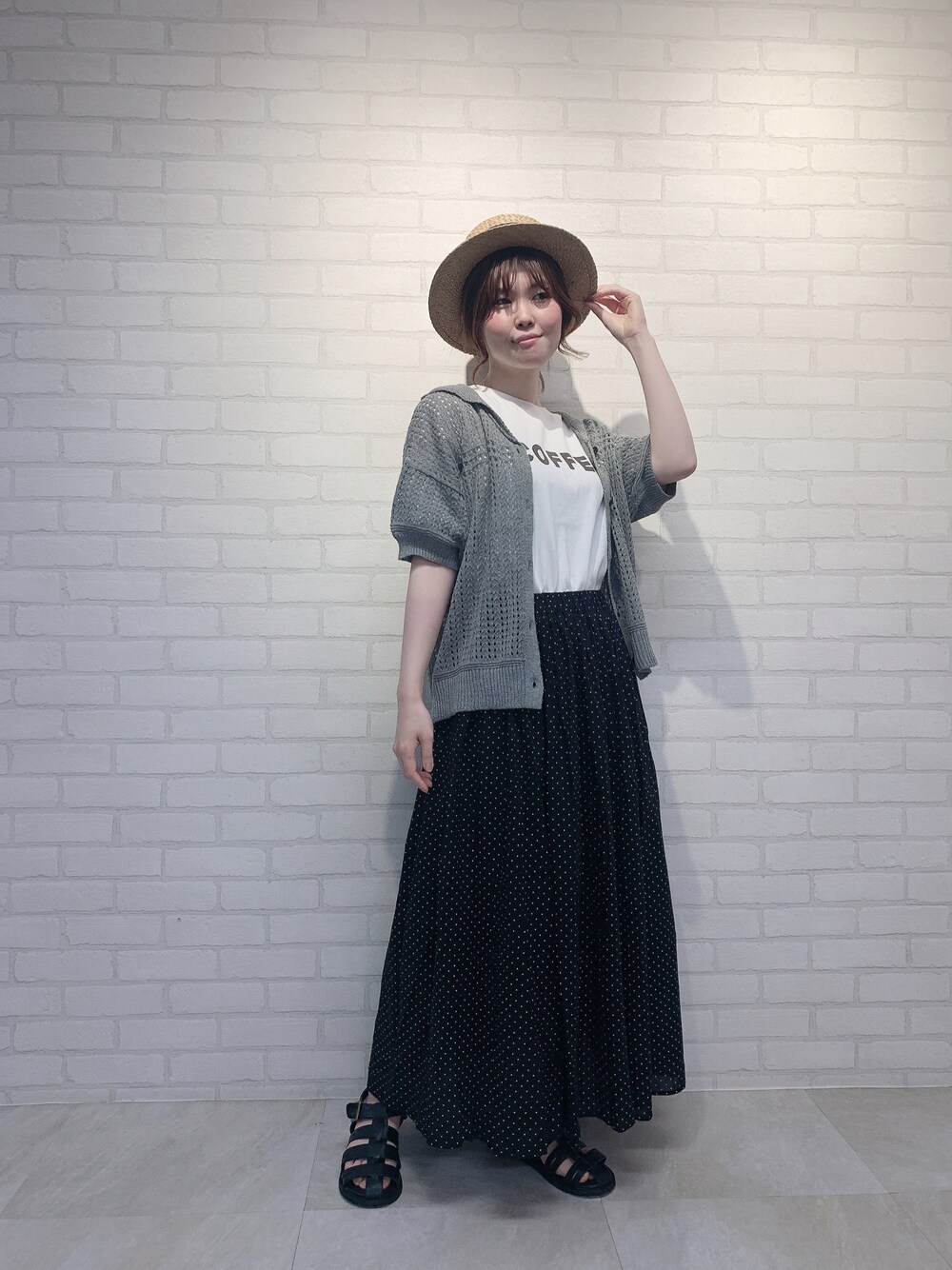 ブラック系のスカート、グレー系のニット/セーター、ホワイト系のTシャツ/カットソーを着用したレディースの春コーディネートの1枚目の写真