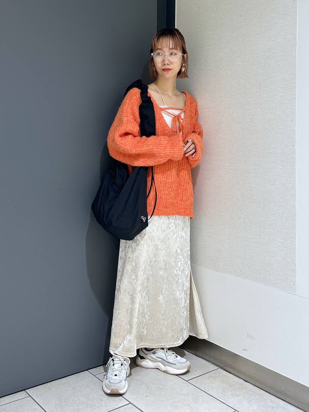 ホワイト系のタンクトップ、オレンジ系のニット/セーター、ホワイト系のスカートを着用したレディースの秋コーディネートの1枚目の写真