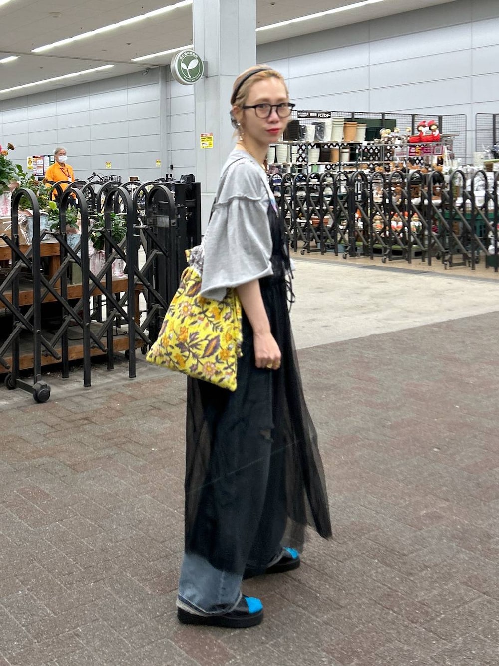 ブラック系のサンダル、ブルー系のデニムパンツ、イエロー系のトートバッグを着用したレディースの春コーディネートの1枚目の写真