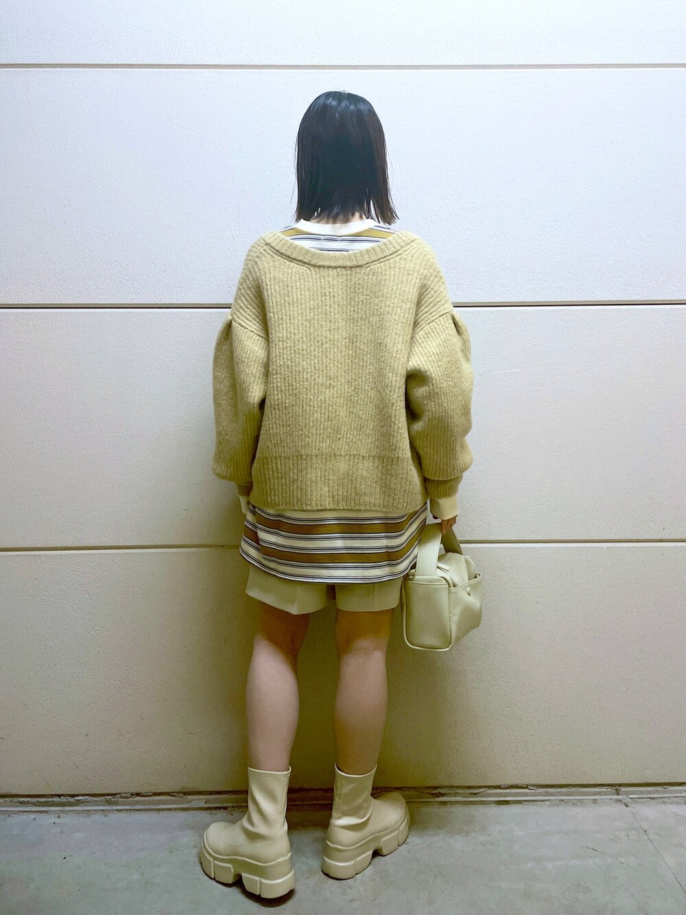 イエロー系のニット/セーター、ホワイト系のスウェット、ホワイト系のその他パンツを着用したレディースの冬コーディネートの3枚目の写真