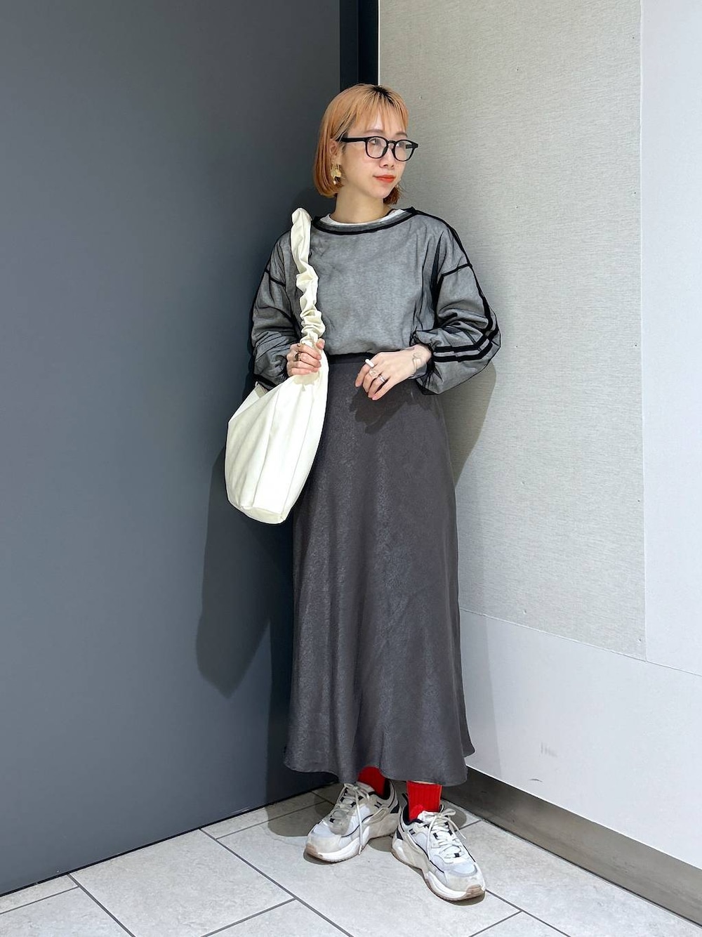 ベージュ系のトートバッグ、ブラック系のTシャツ/カットソー、グレー系のスカートを着用したレディースの春コーディネートの1枚目の写真