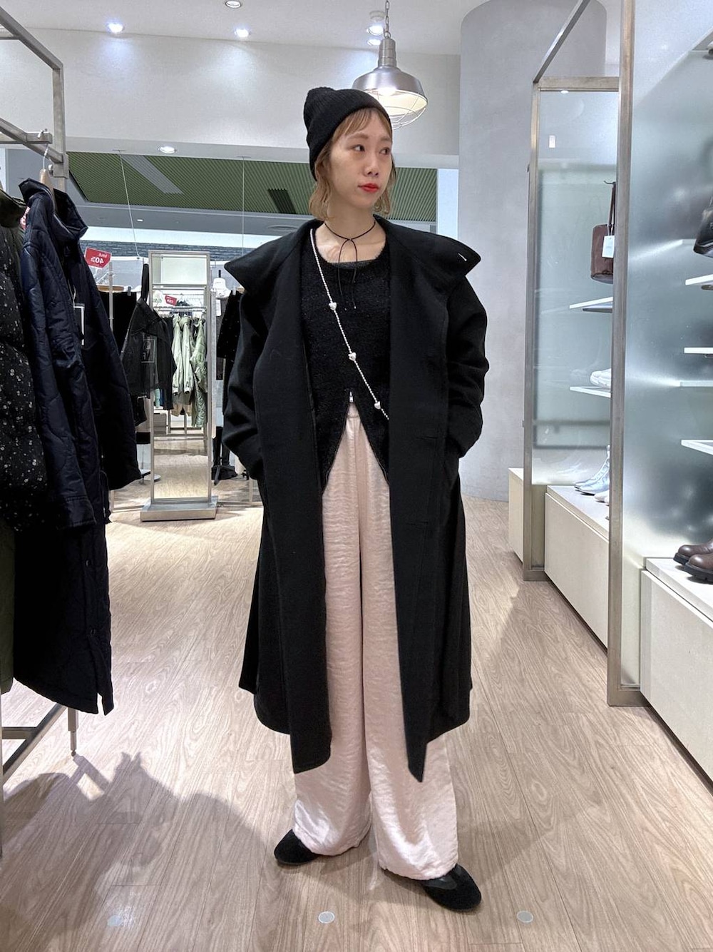 ブラック系のステンカラーコート、ピンク系のカーゴパンツ、ブラック系のニット/セーターを着用したレディースの冬コーディネートの1枚目の写真