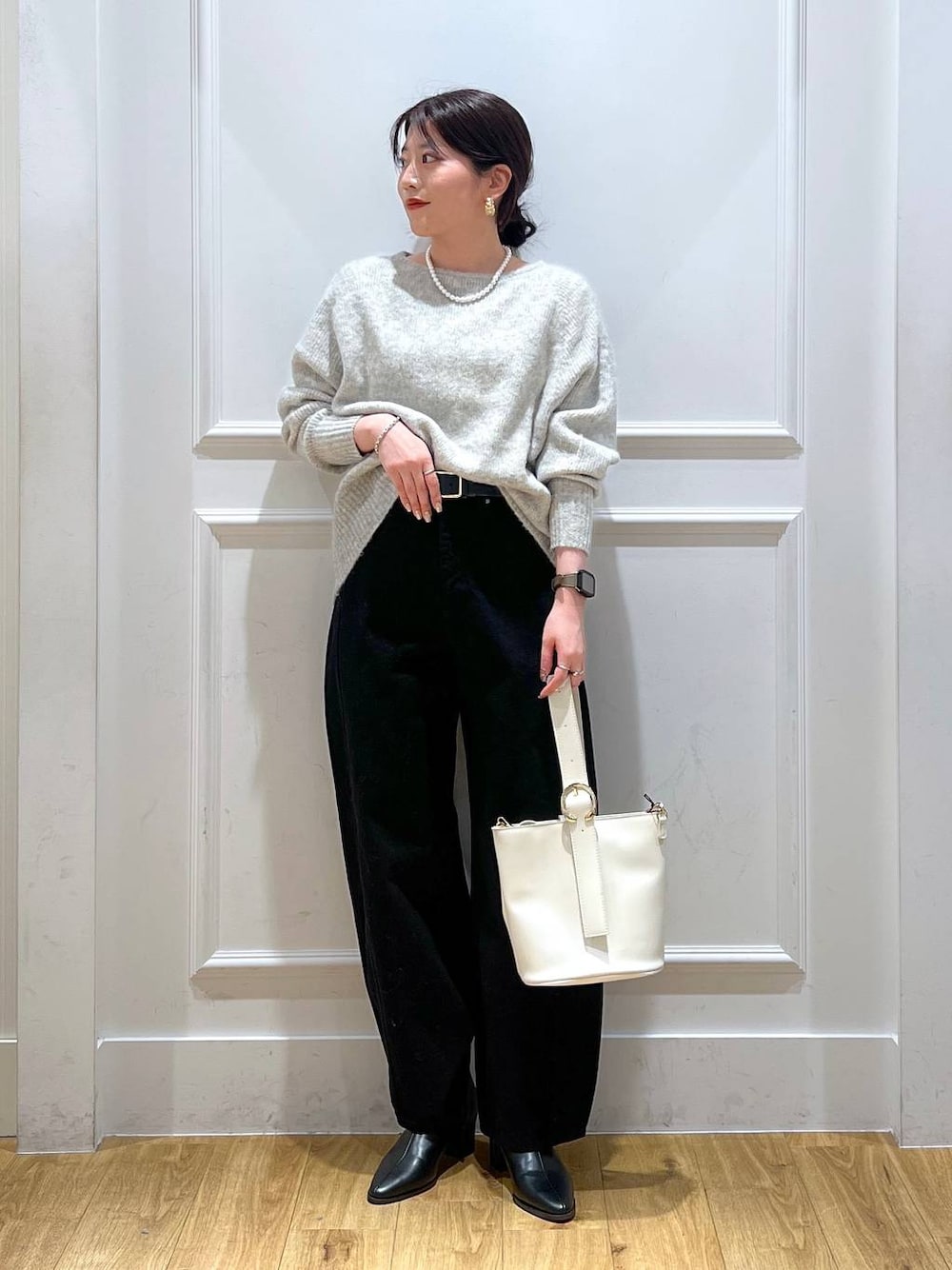 ブラック系のデニムパンツ、ブラック系のブーツ、グレー系のニット/セーターを着用したレディースの冬コーディネートの1枚目の写真