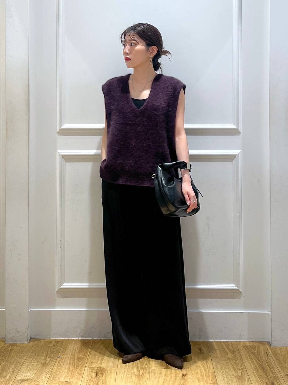 ブラック系のハンドバッグ、ブラック系のスラックス、レッド系のベストを着用したレディースの秋コーディネートの1枚目の写真