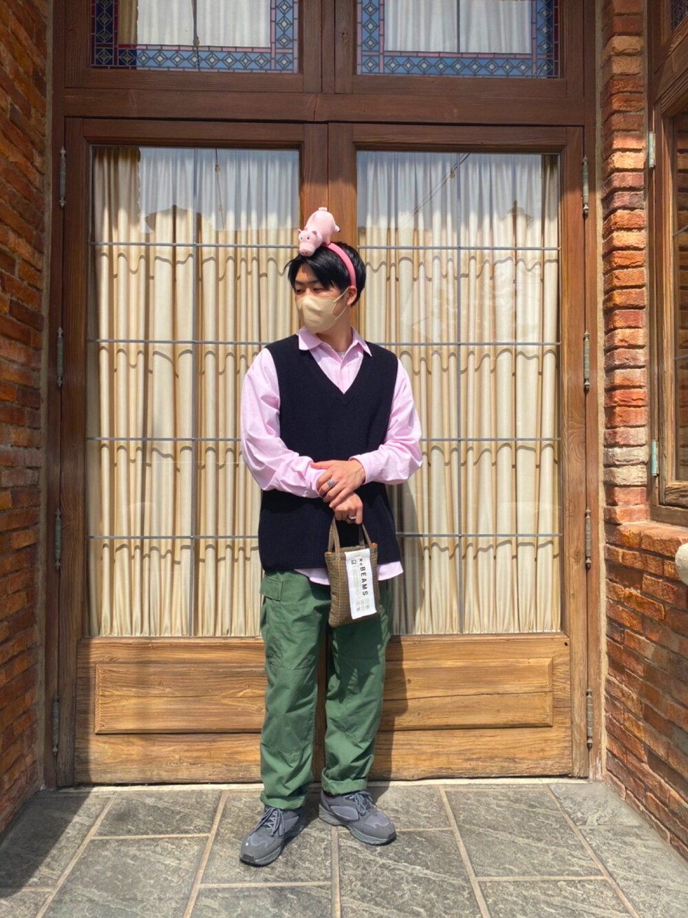 ピンク系のシャツ/ブラウス、ブラック系のベスト、ブラウン系のバッグを着用したメンズの春コーディネートの1枚目の写真