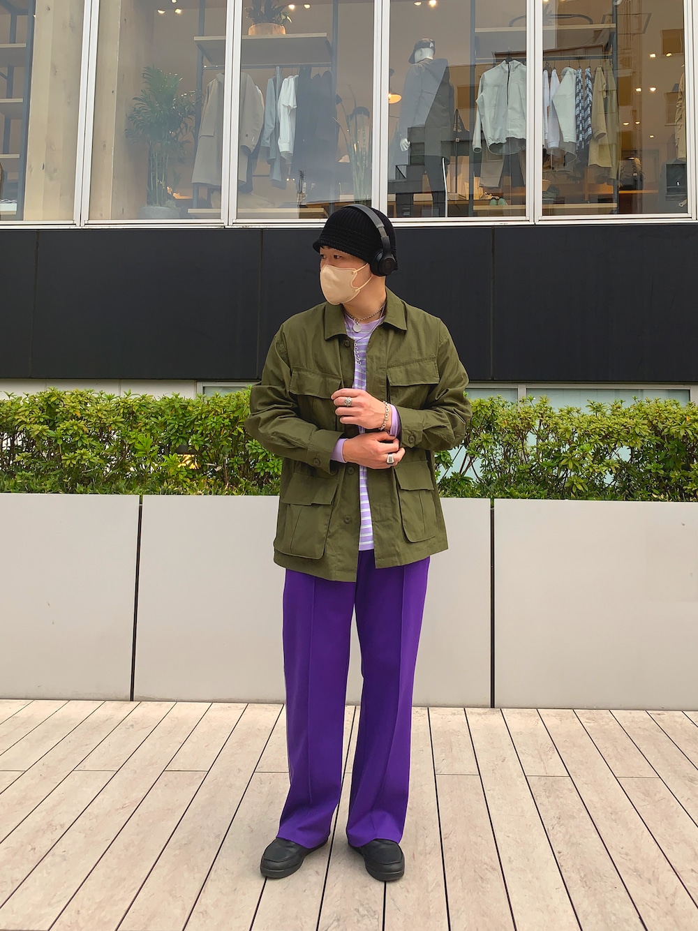 グリーン系のミリタリージャケット、パープル系のスラックス、ブラック系のスニーカーを着用したメンズの春コーディネートの1枚目の写真