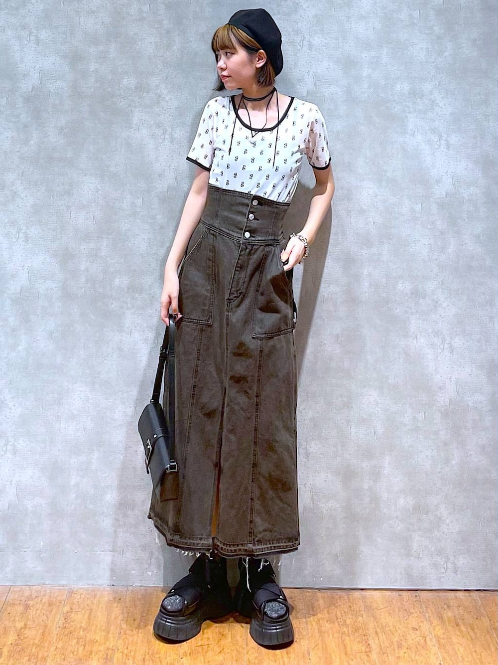 ブラック系のスニーカー、ブラック系のデニムスカート、ブラック系のハンドバッグを着用したレディースの夏コーディネートの1枚目の写真