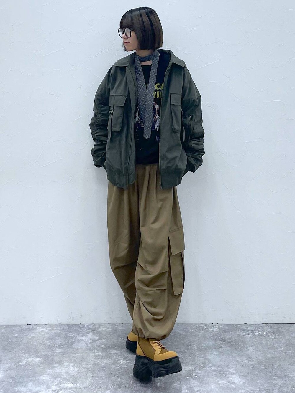 グレー系のネクタイ、ブラウン系のブーツ、グリーン系のブルゾンを着用したレディースの秋コーディネートの1枚目の写真