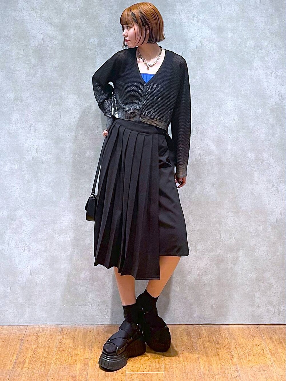 ブラック系のスニーカー、ブルー系のタンクトップ、ブラック系のスカートを着用したレディースの夏コーディネートの1枚目の写真