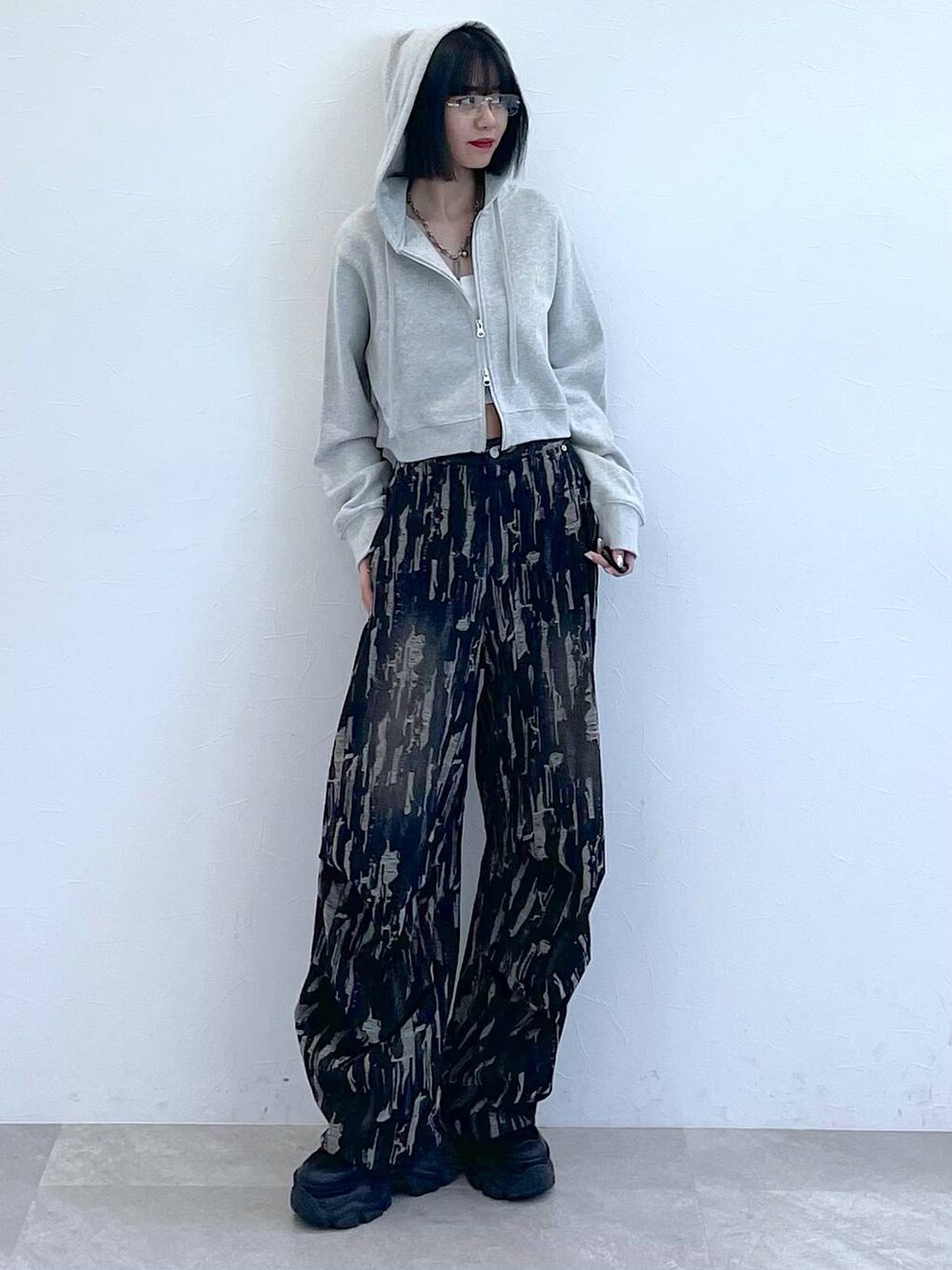 グレー系のパーカー、ホワイト系のキャミソール、ブラック系のスニーカーを着用したレディースの秋コーディネートの1枚目の写真