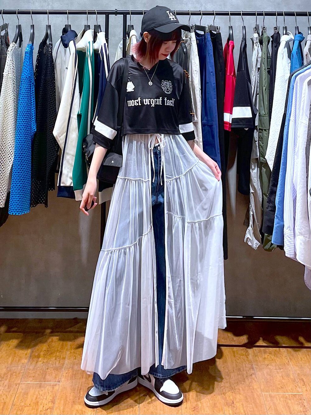 ブラック系のショルダーバッグ、ブルー系のデニムパンツ、ホワイト系のワンピースを着用したレディースの春コーディネートの1枚目の写真