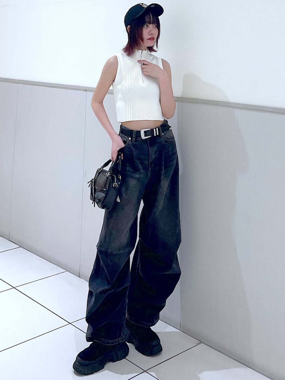 ブラック系のデニムパンツ、ホワイト系のニット/セーター、ブラック系のボストンバッグを着用したレディースの春コーディネートの1枚目の写真