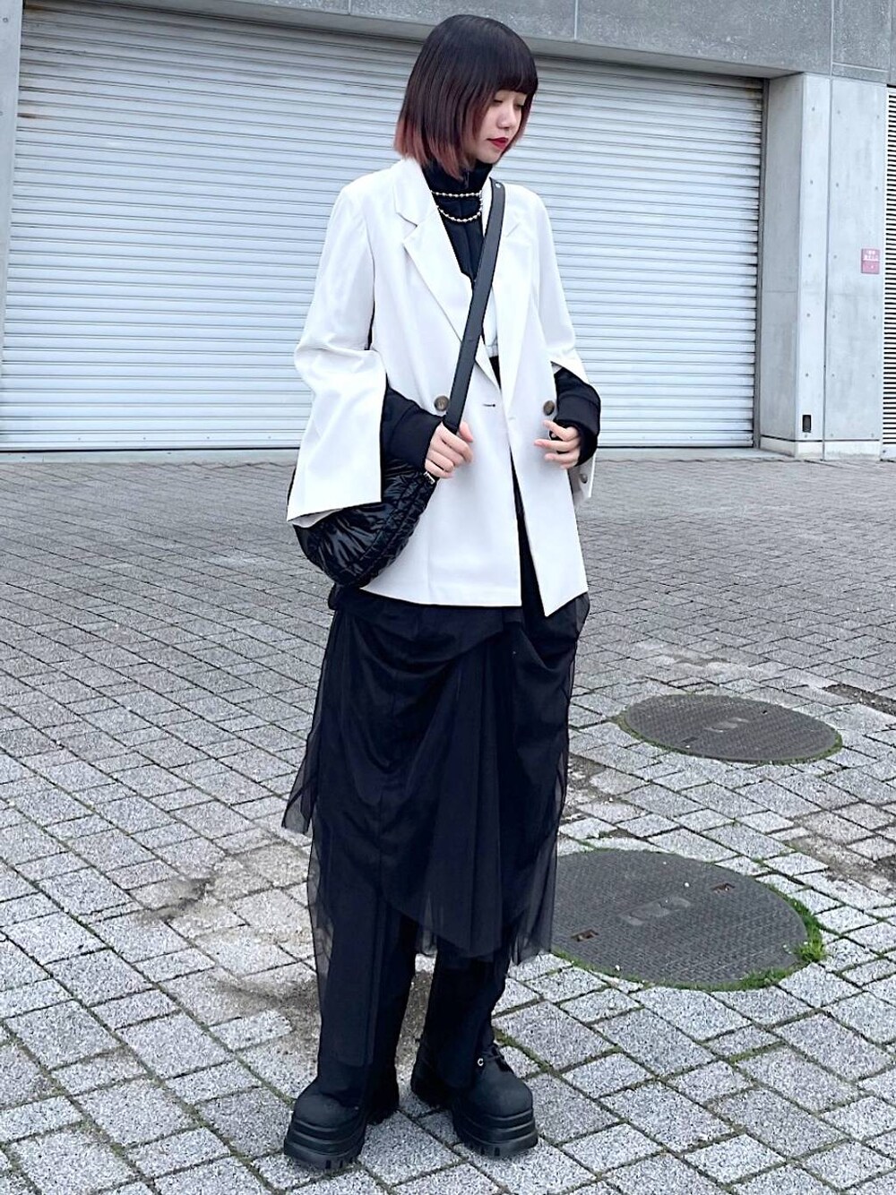 ブラック系のショルダーバッグ、ブラック系のナイロンジャケット、ブラック系のスカートを着用したレディースの春コーディネートの1枚目の写真