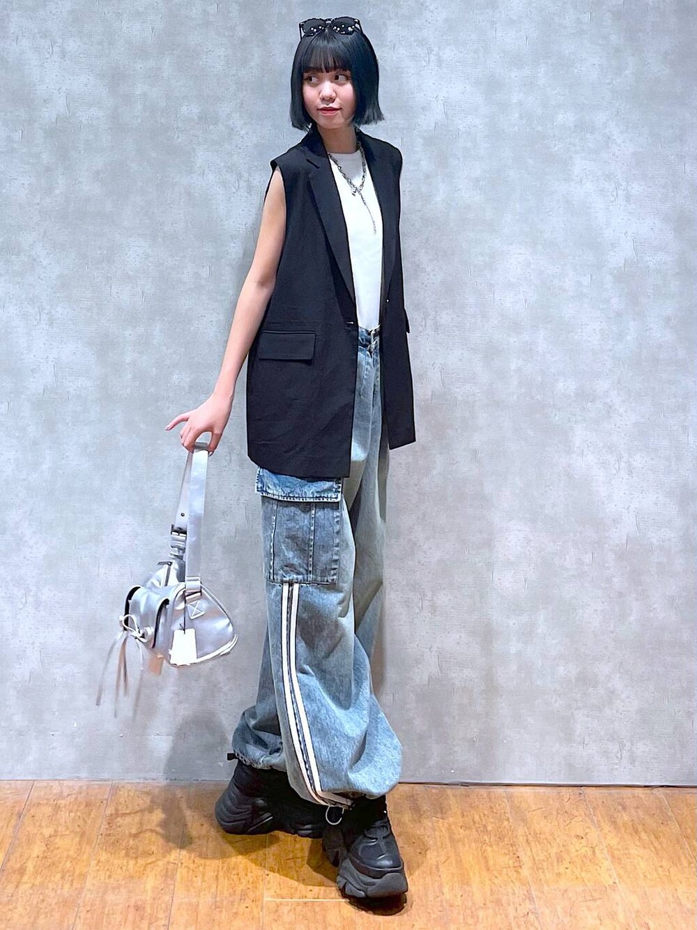 ブラック系のスニーカー、ブルー系のデニムパンツ、ホワイト系のタンクトップを着用したレディースの夏コーディネートの1枚目の写真