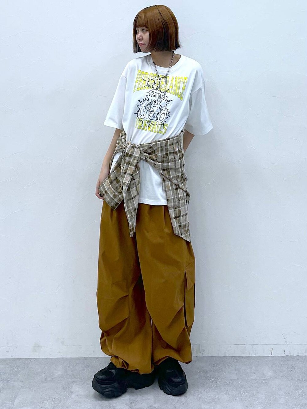 ブラック系のスニーカー、ブラウン系のカーゴパンツ、ホワイト系のTシャツ/カットソーを着用したレディースの夏コーディネートの1枚目の写真