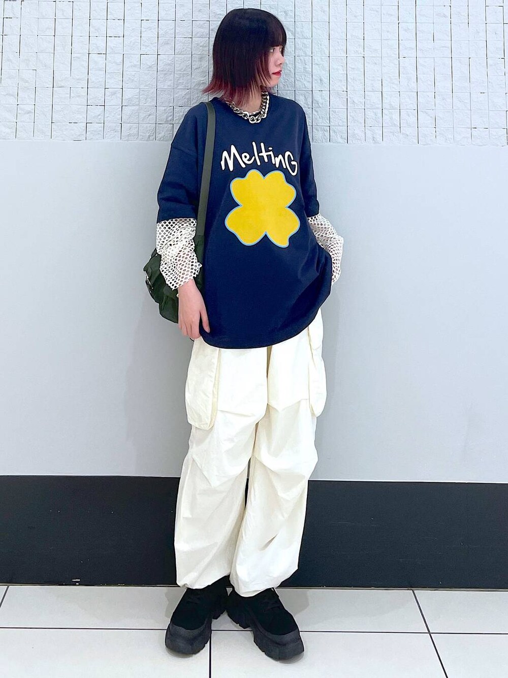グリーン系のショルダーバッグ、ホワイト系のカーゴパンツ、ブラック系のブーツを着用したレディースの春コーディネートの1枚目の写真