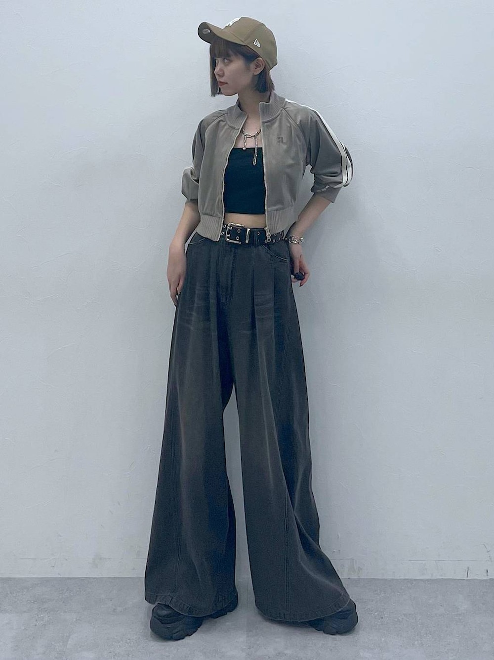 ブラック系のスニーカー、ブラック系のキャミソール、ブラック系のデニムパンツを着用したレディースの秋コーディネートの1枚目の写真