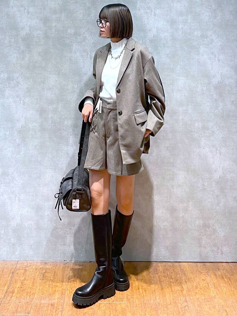 ブラック系のショルダーバッグ、ホワイト系のニット/セーター、ブラック系のブーツを着用したレディースの秋コーディネートの1枚目の写真