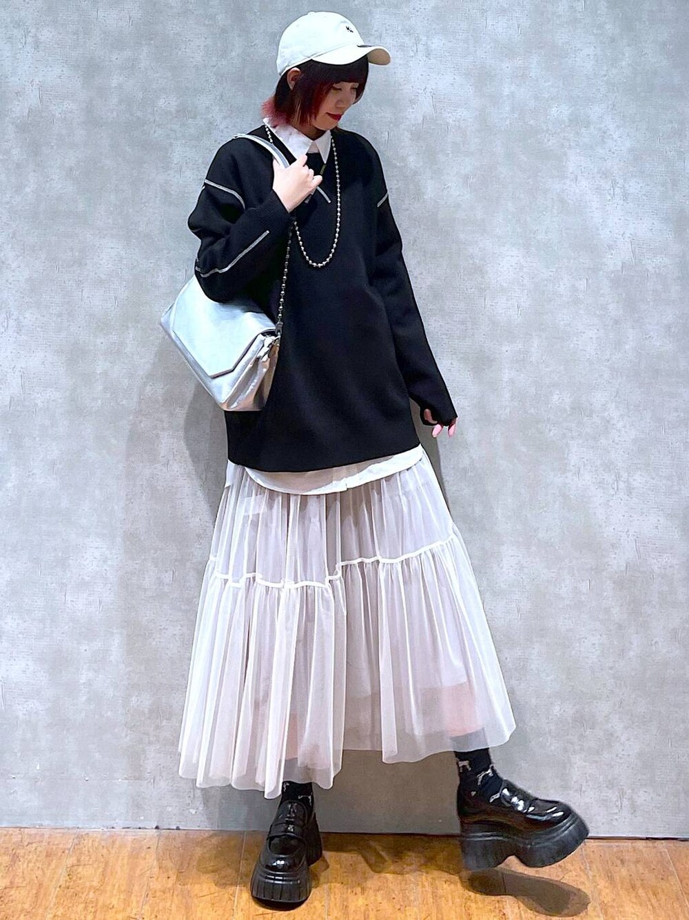 シルバー系のショルダーバッグ、ホワイト系のシャツ/ブラウス、ブラック系のニット/セーターを着用したレディースの春コーディネートの1枚目の写真