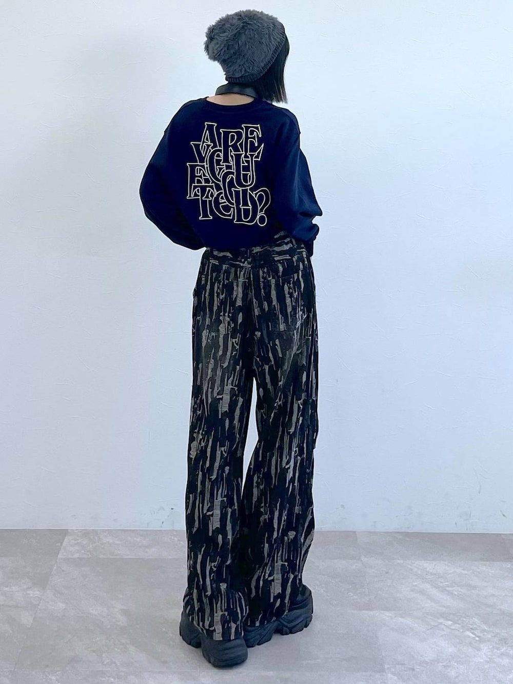 ブラック系のスニーカー、ブラック系のデニムパンツ、ホワイト系のキャミソールを着用したレディースの秋コーディネートの1枚目の写真