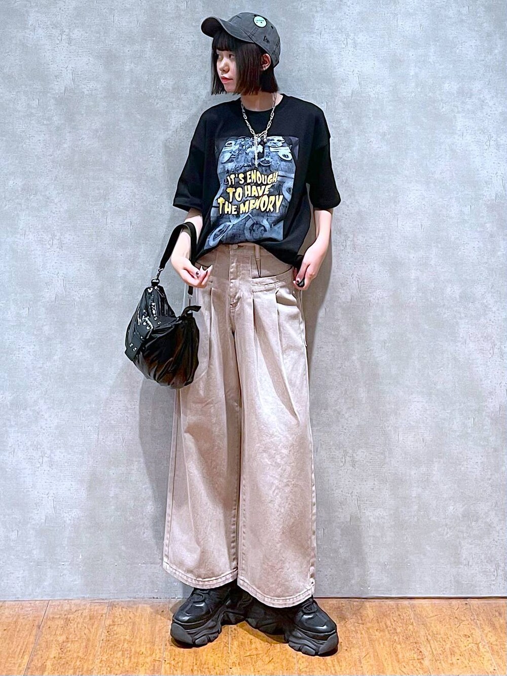 ブラック系のスニーカー、ブラック系のショルダーバッグ、ベージュ系のデニムパンツを着用したレディースの夏コーディネートの1枚目の写真