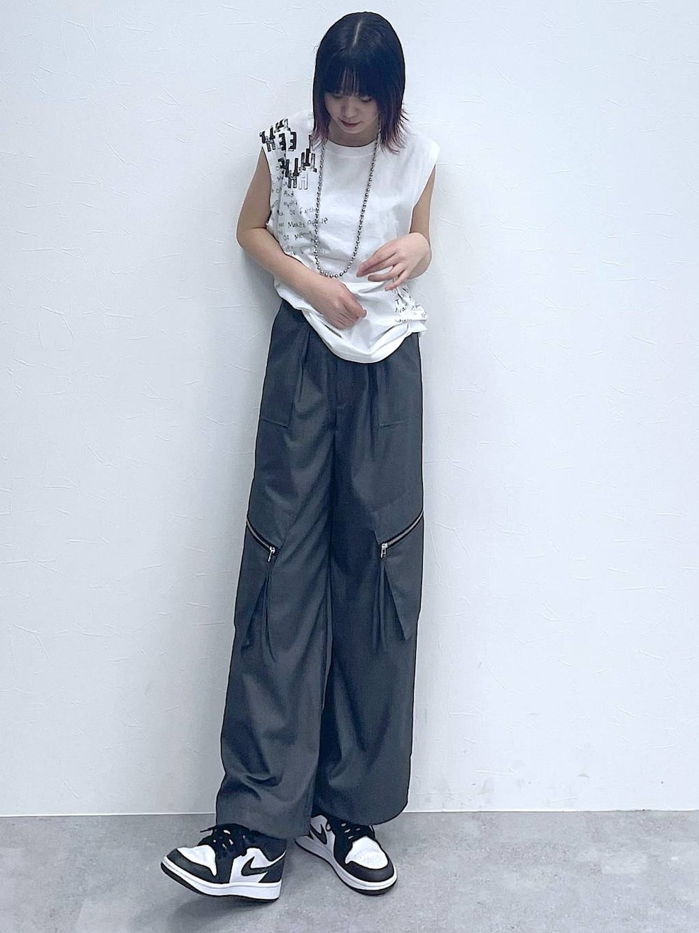 グレー系のスラックス、ホワイト系のTシャツ/カットソー、シルバー系のネックレスを着用したレディースの夏コーディネートの1枚目の写真