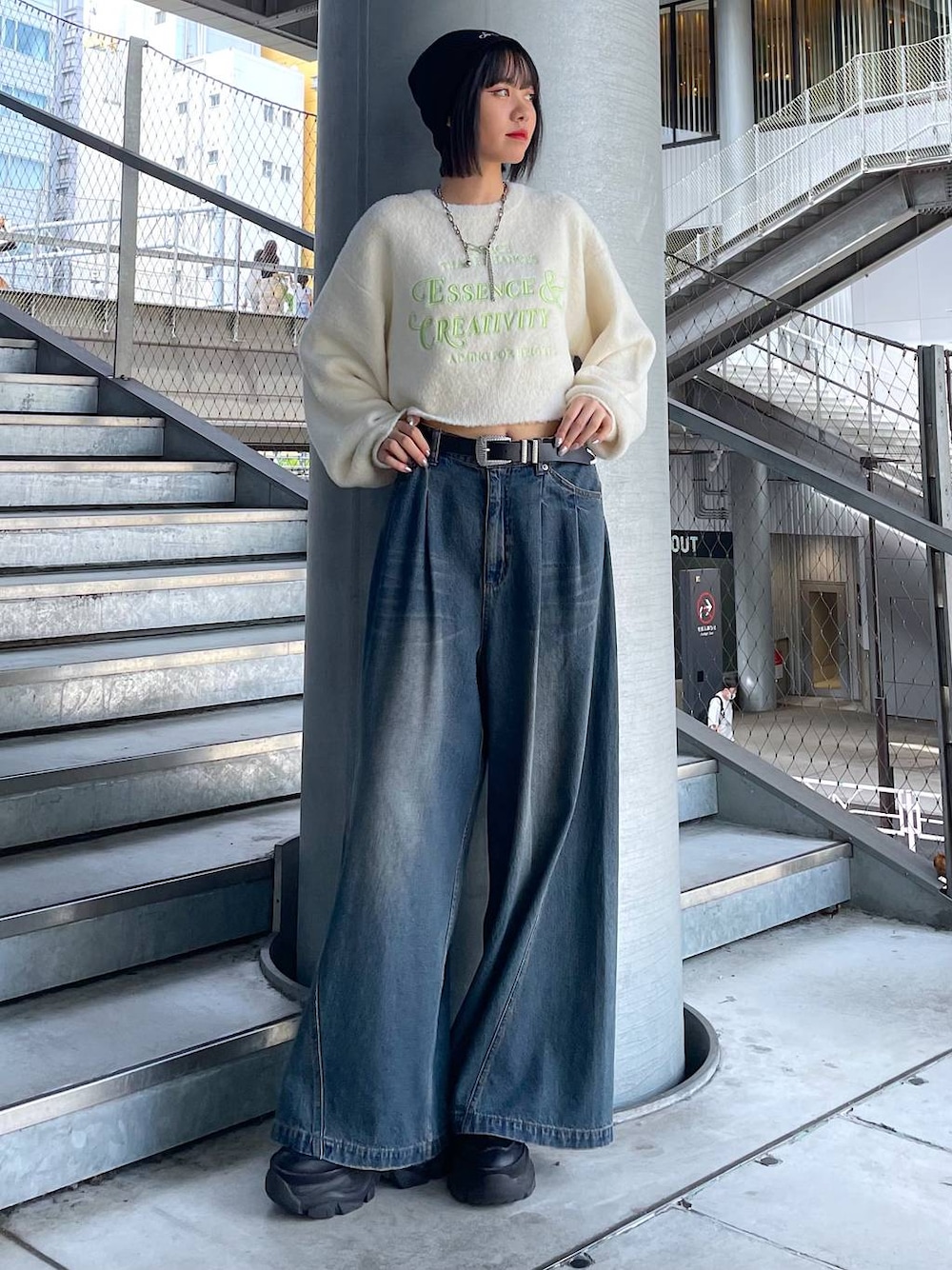 ブラック系のスニーカー、ブルー系のデニムパンツ、ホワイト系のニット/セーターを着用したレディースの秋コーディネートの1枚目の写真