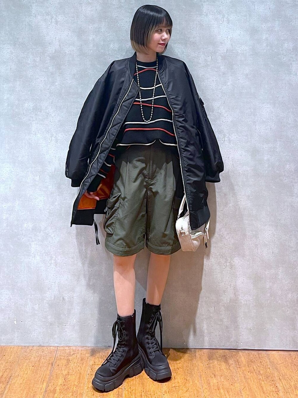 グリーン系のカーゴパンツ、ブラック系のMA-1、ブラック系のニット/セーターを着用したレディースの冬コーディネートの1枚目の写真