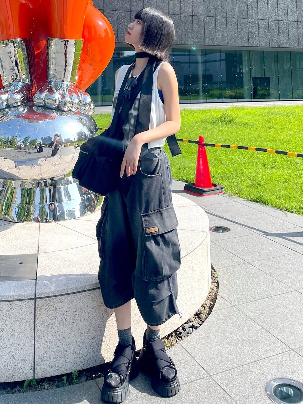ブラック系のスニーカー、ブラック系のショルダーバッグ、ホワイト系のTシャツ/カットソーを着用したレディースの夏コーディネートの1枚目の写真