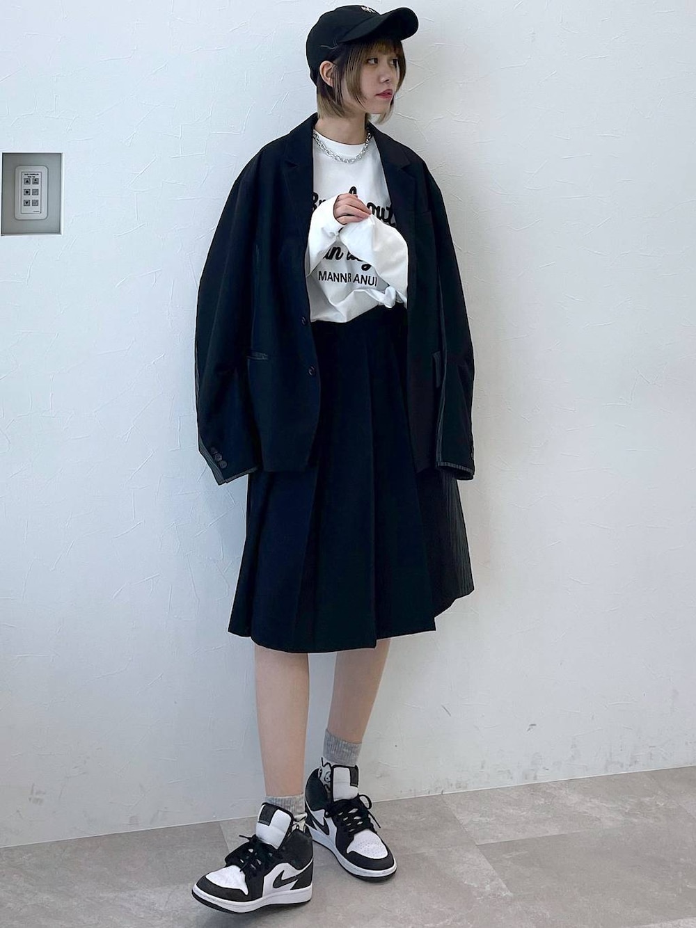 ブラック系のテーラードジャケット、ブラック系のスラックス、ブラック系のキャップを着用したレディースの冬コーディネートの1枚目の写真