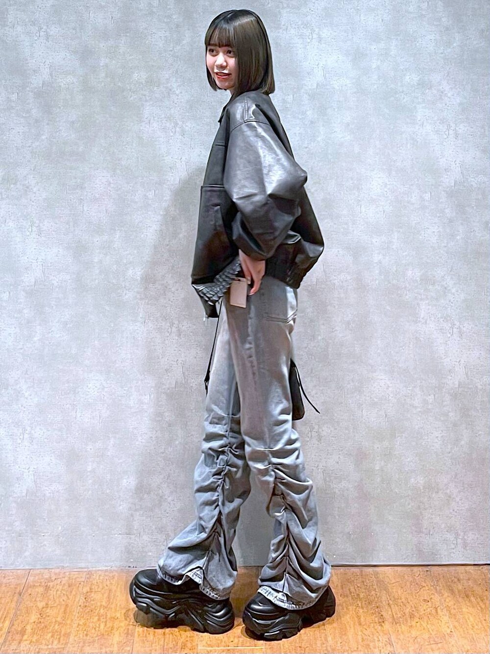 ブラック系のスニーカー、ブラック系のショルダーバッグ、ブルー系のデニムパンツを着用したレディースの秋コーディネートの1枚目の写真