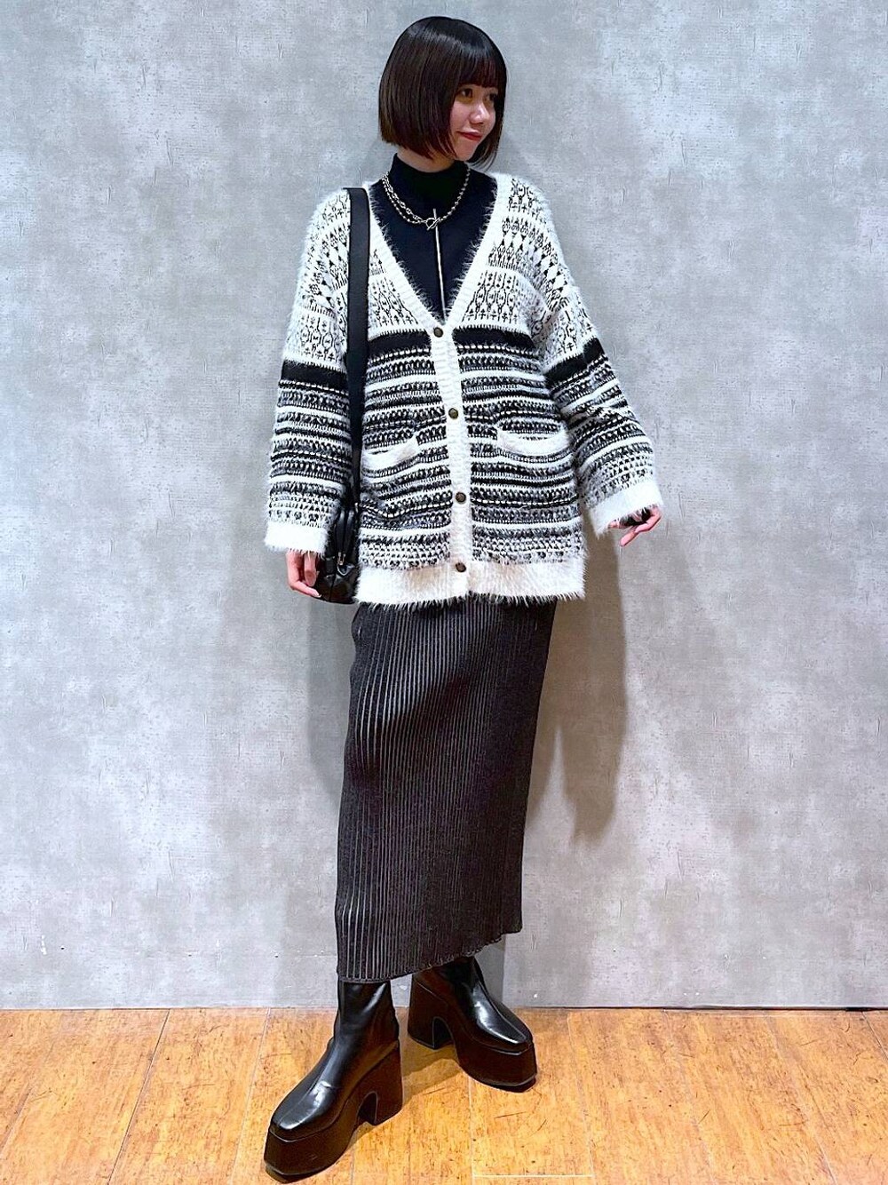 ブラック系のニット/セーター、ブラック系のブーツ、ブラック系のショルダーバッグを着用したレディースの冬コーディネートの1枚目の写真