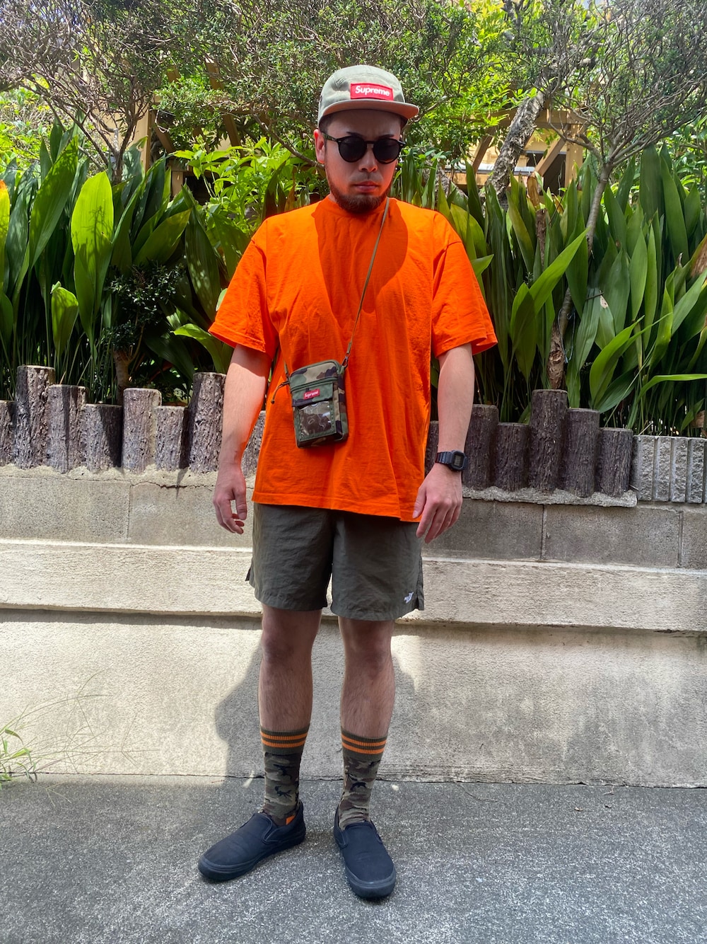 オレンジ系のTシャツ/カットソー、グリーン系のショルダーバッグ、グリーン系のその他パンツを着用したメンズの夏コーディネートの1枚目の写真