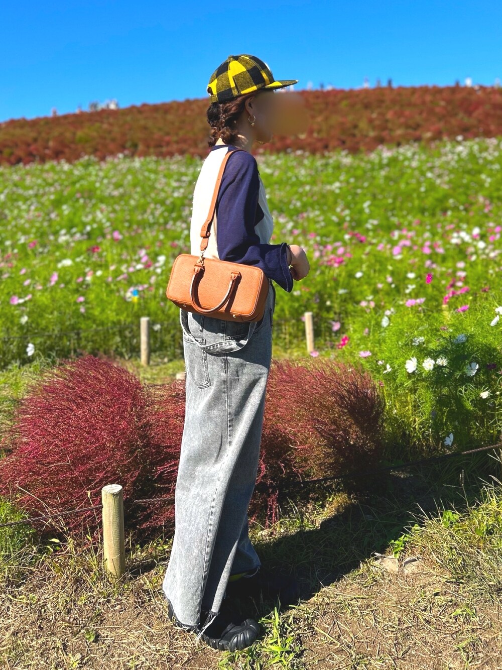 ブルー系のTシャツ/カットソー、ブラウン系のボストンバッグ、ブラック系のジャンパースカートを着用したレディースの秋コーディネートの1枚目の写真