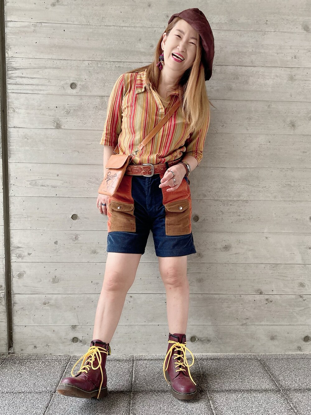 オレンジ系のトップス、ブラウン系のブーツ、ブラウン系のパンツを着用したレディースの夏コーディネートの1枚目の写真