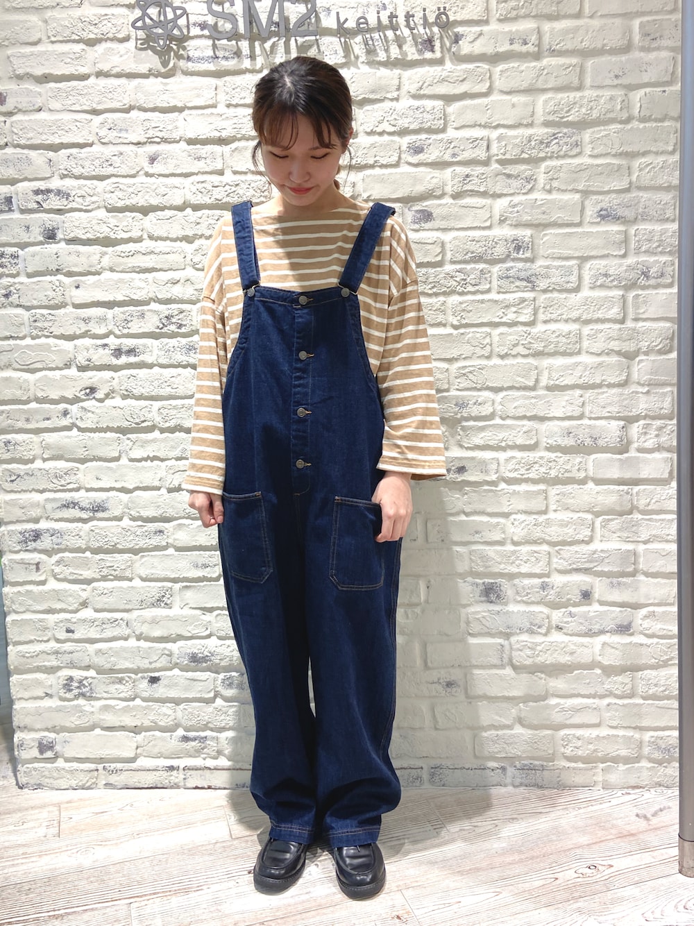 ブラック系のドレスシューズ、ブルー系のサロペット/オーバーオール、ベージュ系のTシャツ/カットソーを着用したレディースの秋コーディネートの1枚目の写真