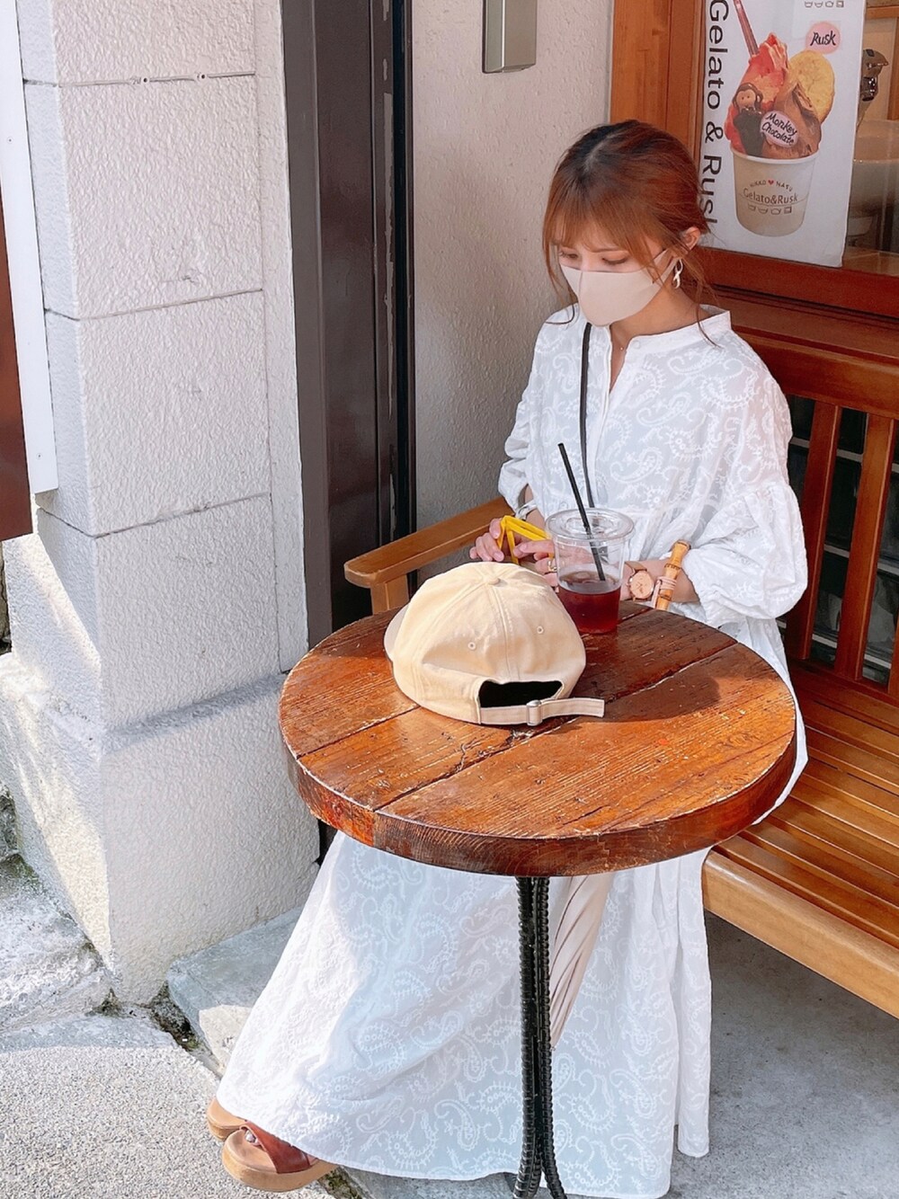 ホワイト系のワンピース、ブラウン系のサンダル、ベージュ系のキャップを着用したレディースの夏コーディネートの1枚目の写真
