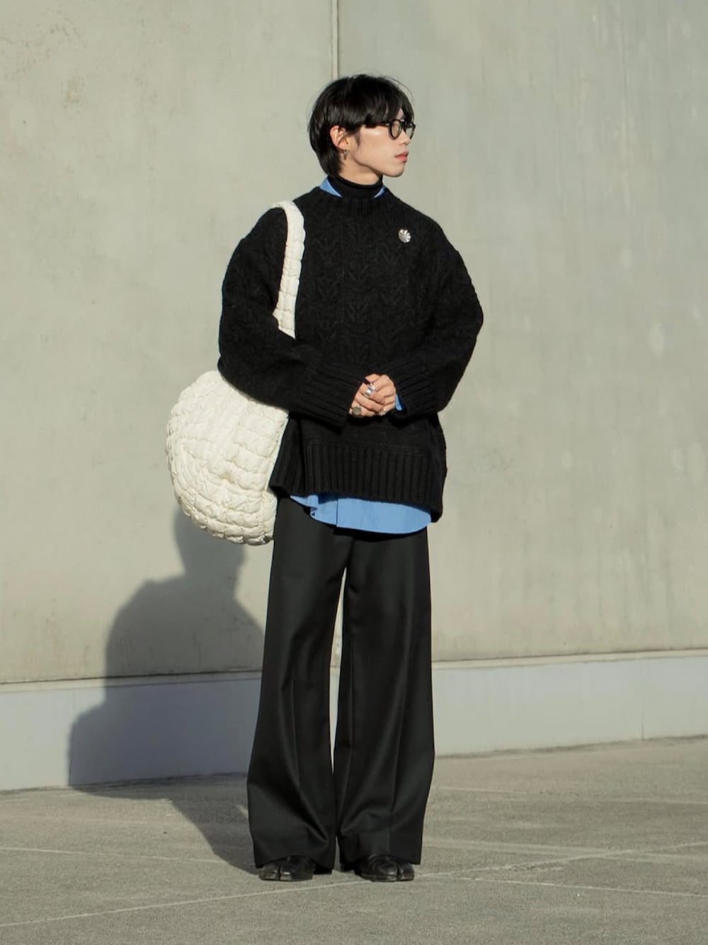 ブラック系のニット/セーター、ブルー系のシャツ/ブラウス、ブラック系のスラックスを着用したメンズの秋コーディネートの1枚目の写真