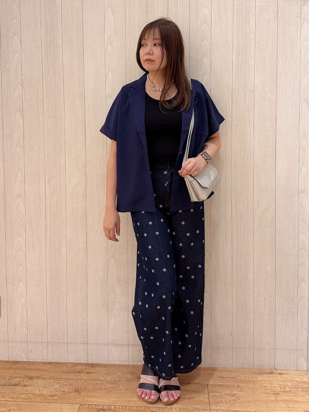 ブラック系のタンクトップ、ブルー系のテーラードジャケット、ブルー系のデニムパンツを着用したレディースの秋コーディネートの1枚目の写真