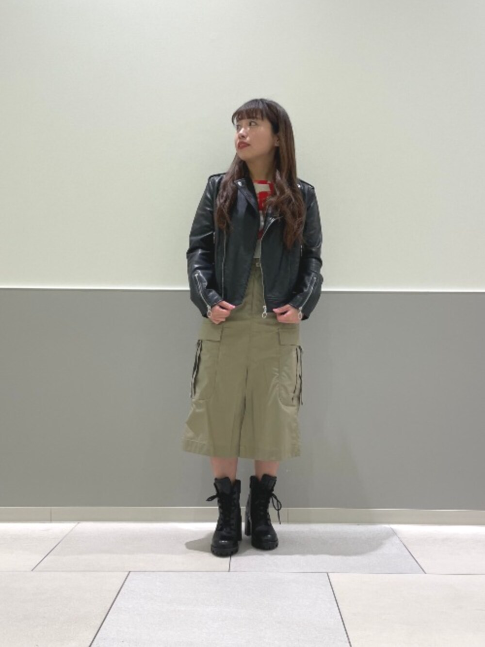 ブラック系のライダースジャケット、ブラウン系のスカート、ホワイト系のTシャツ/カットソーを着用したレディースの春コーディネートの1枚目の写真