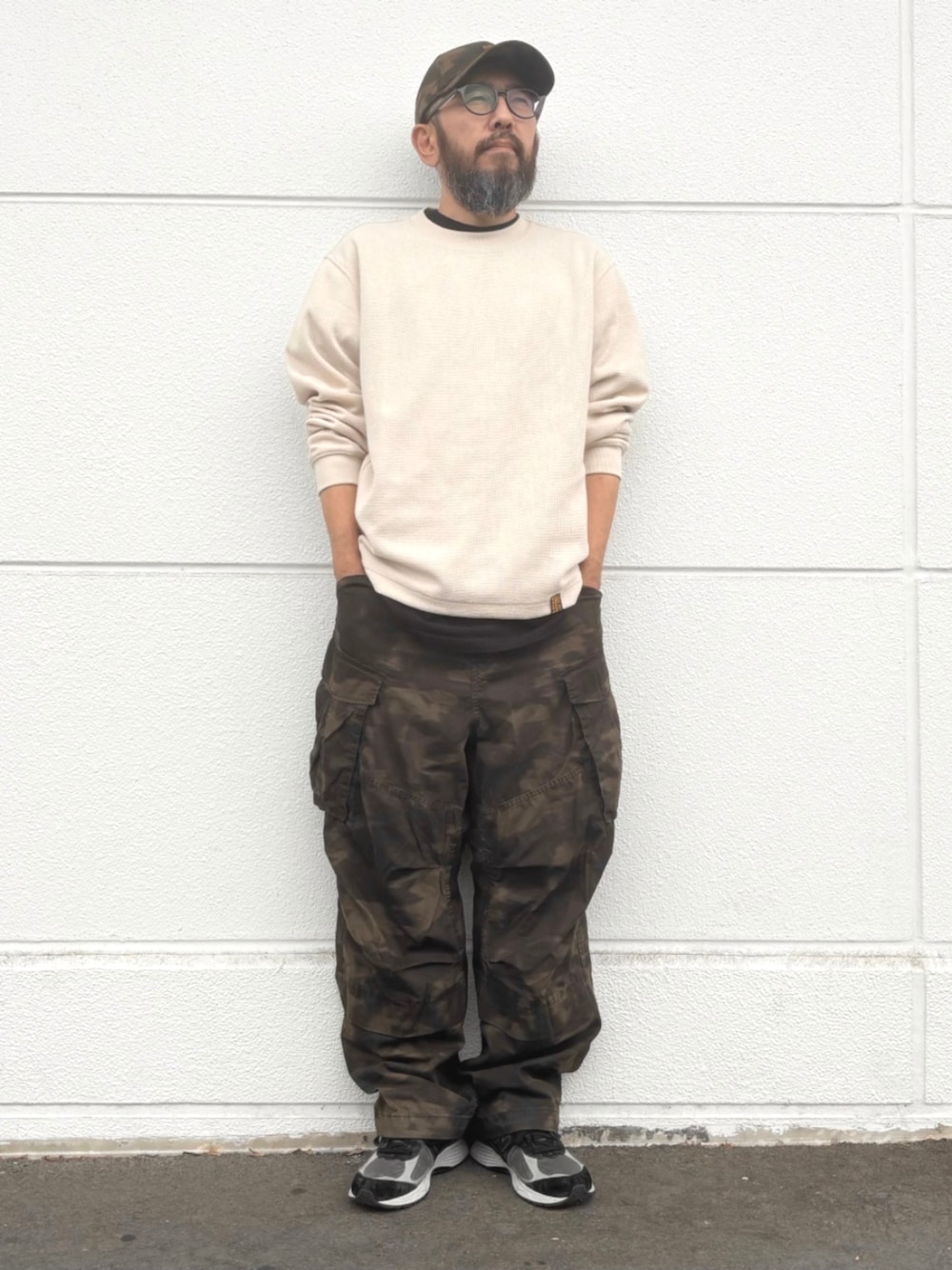 ホワイト系のTシャツ/カットソー、グリーン系のカーゴパンツ、ブラウン系のキャップを着用したメンズの秋コーディネートの1枚目の写真