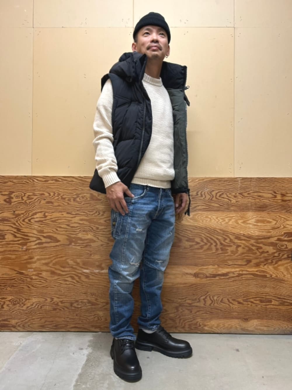 ブラック系のドレスシューズ、ブルー系のダウンベスト、ベージュ系のニット/セーターを着用したメンズの秋コーディネートの1枚目の写真