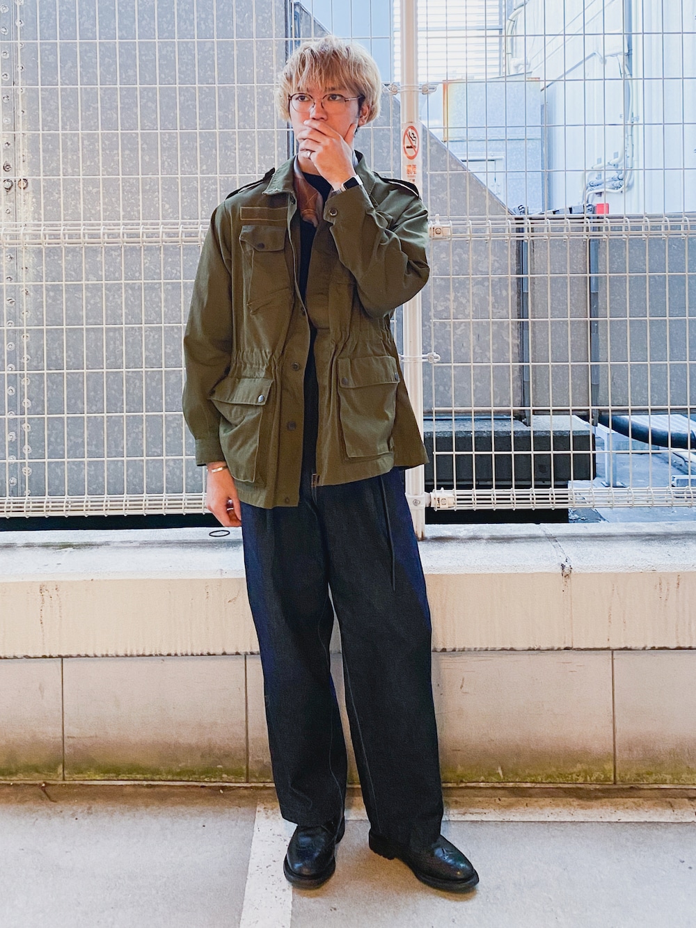 グリーン系のミリタリージャケット、ブルー系のデニムパンツ、ブラック系のドレスシューズを着用したメンズの秋コーディネートの1枚目の写真