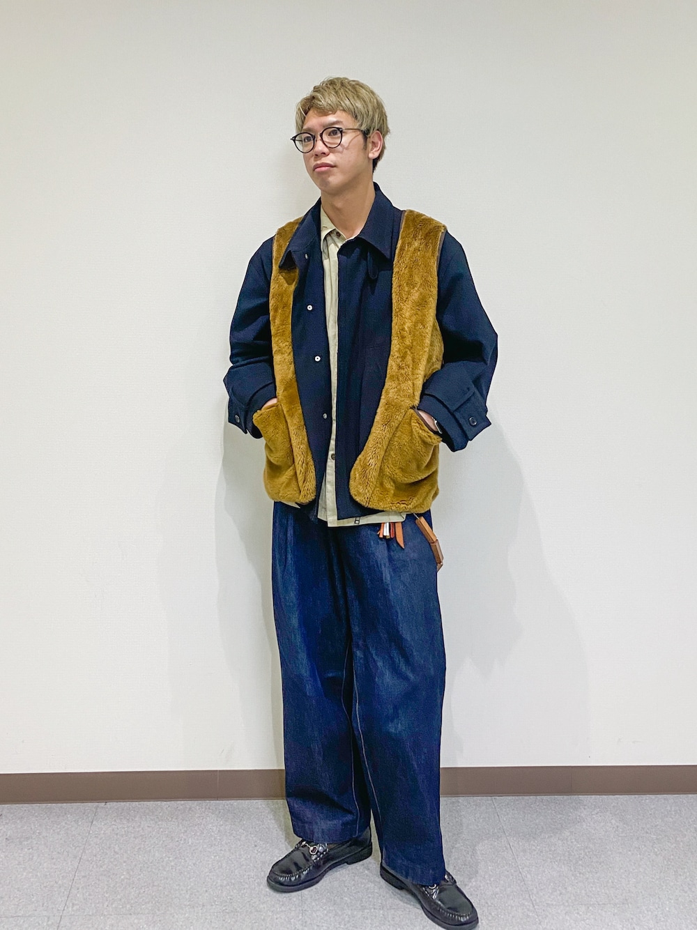 ブラック系のブルゾン、ブラウン系のベスト、ブルー系のデニムパンツを着用したメンズの春コーディネートの1枚目の写真